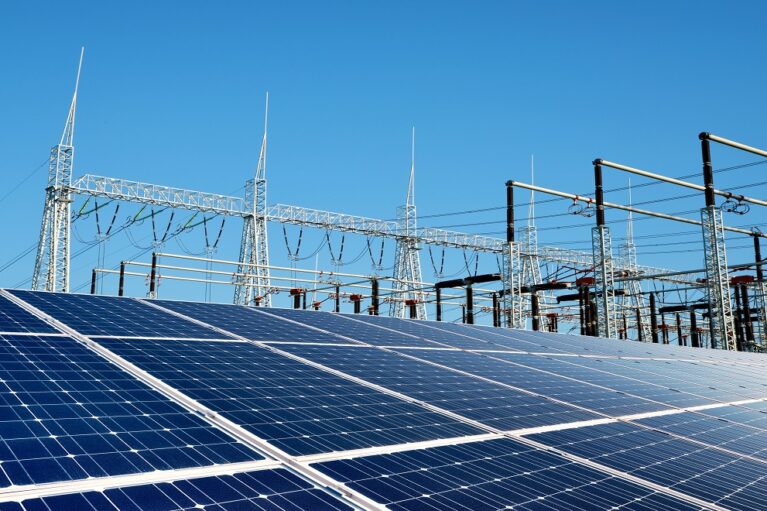 Solar energy panels in the background high voltage power substation.